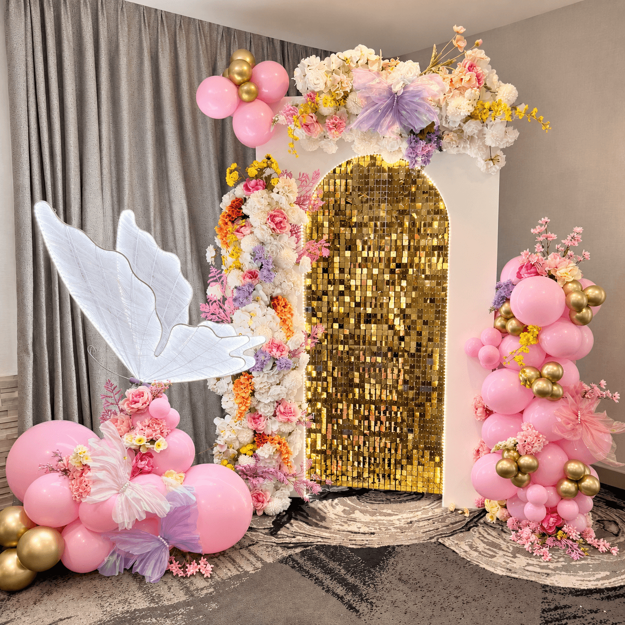 Pink floral butterfly installation around a gold sequin backdrop