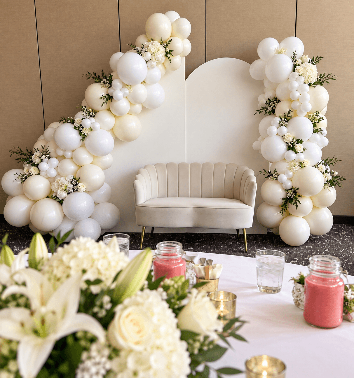 White floral balloon backdrop with a loveseat and styled table