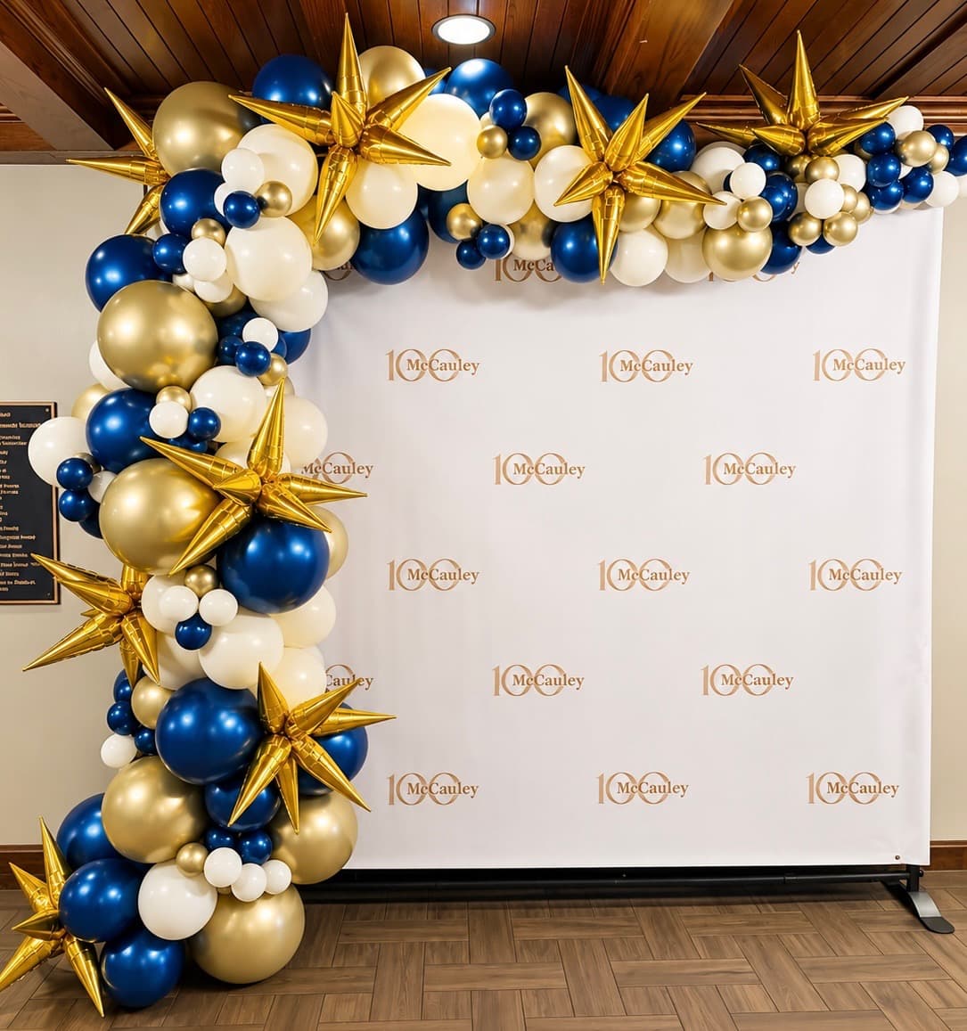 Navy, gold and white balloon installation with branded event backdrop