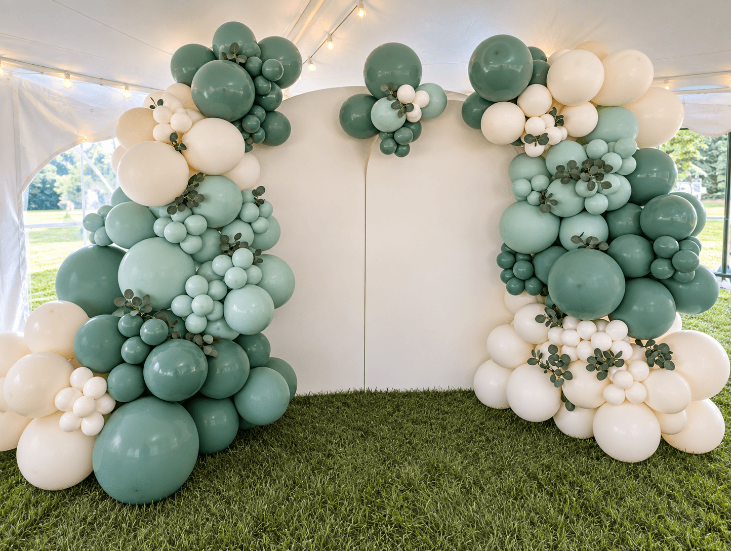 Sage, mint, and cream balloon installation framing a white backdrop