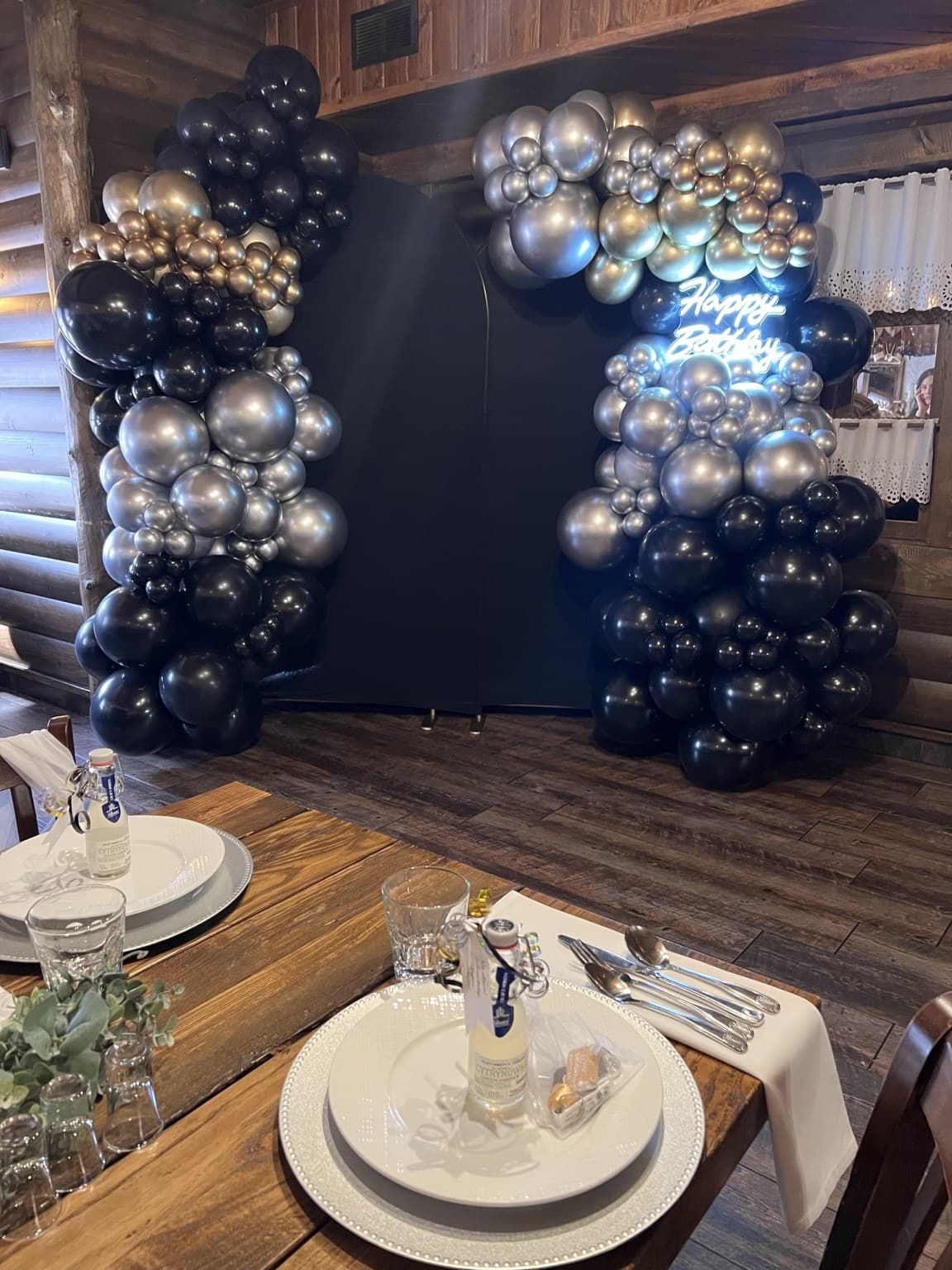 Styled dining table beside a navy, gold, and silver balloon backdrop